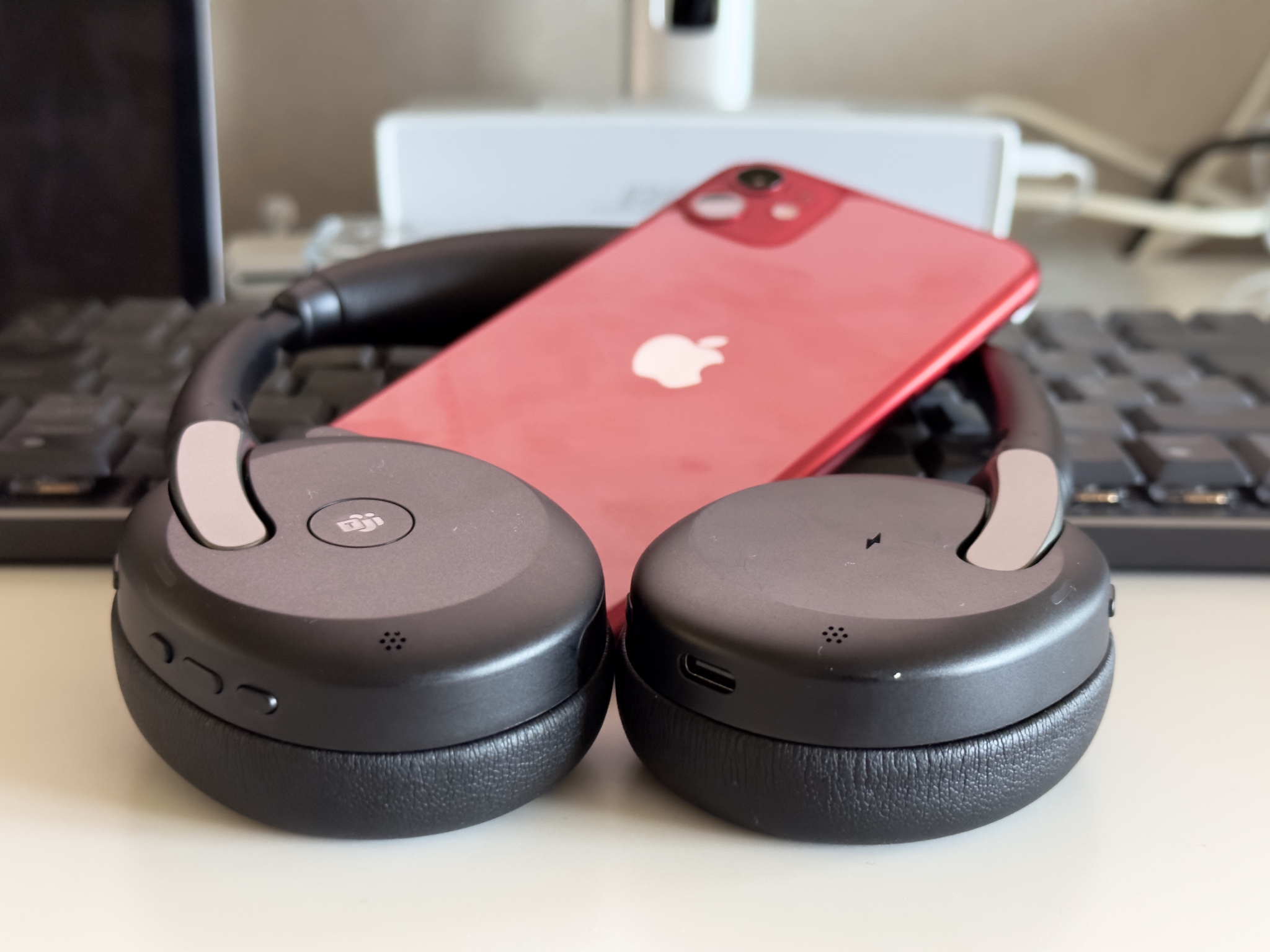 Jabra Evolve2 65 Flex headset med en röd iPhone 11 i mitten.